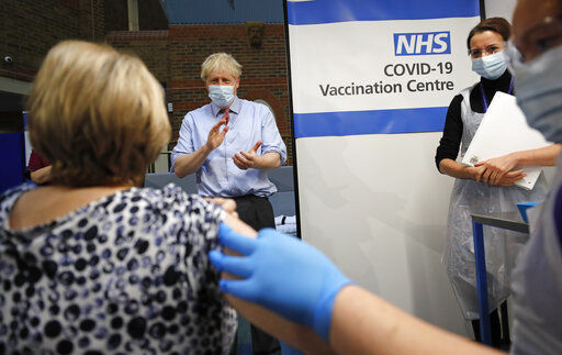 British Prime Minister Boris Johnson applauds after nurse Rebecca Cathersides administered the Pfizer-BioNTech COVID-19 vaccine to Lyn Wheeler at Guy