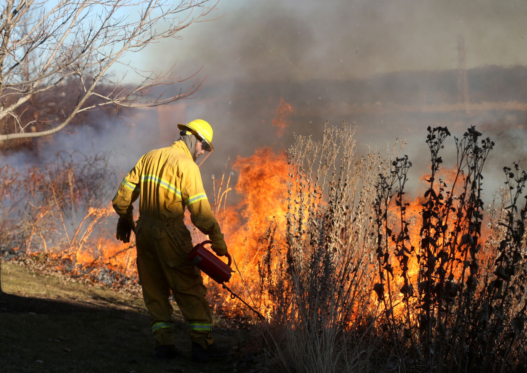 Ben Juran, with Applied Ecological Services, conducts a controlled burn around 16th Street Detention Basin in Dubuque on Wednesday. The burn also included the area of the Lower Bee Branch Creek and is being done to stimulate the growth of native plants and manage invasive species. PHOTO CREDIT: JESSICA REILLY