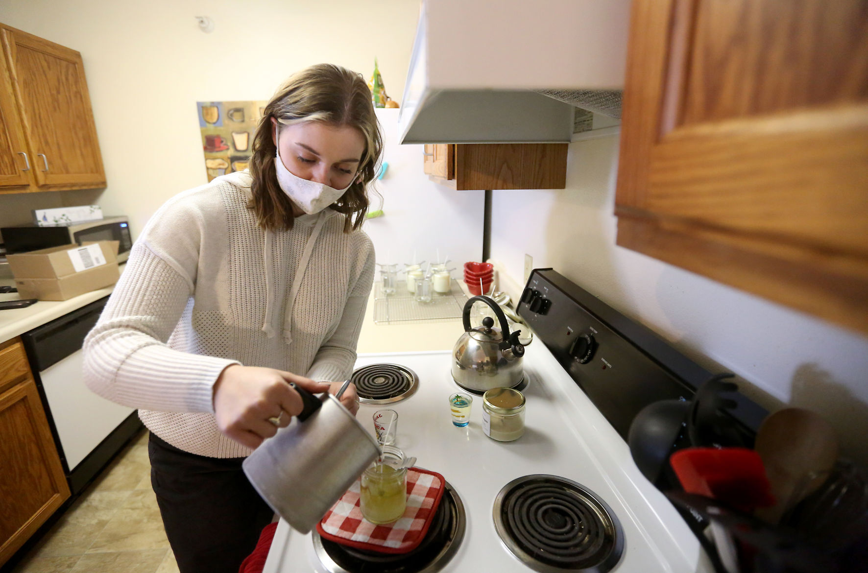 Ali Smith, owner of Ali J. Candles, pours a mixture into jars while making candles at her apartment in Platteville, Wis., on Wednesday, Dec. 30, 2020. PHOTO CREDIT: JESSICA REILLY