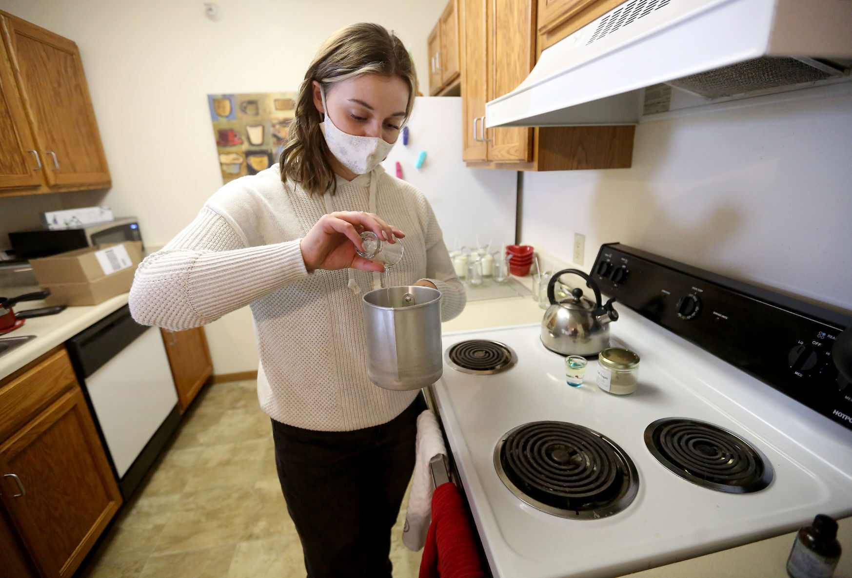 Ali Smith, owner of Ali J. Candles, pours fragrance into a mixture while making candles at her apartment in Platteville, Wis., on Wednesday, Dec. 30, 2020. PHOTO CREDIT: JESSICA REILLY