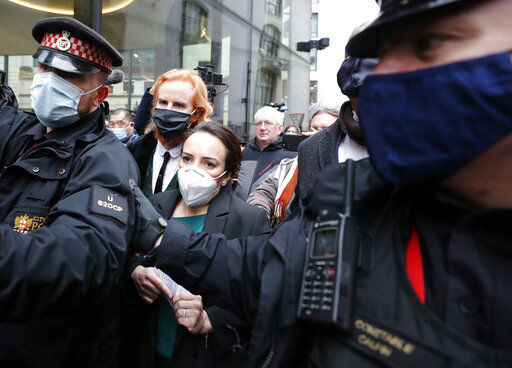 Stella Moris, center left, girlfriend of Julian Assange, is escorted by police after speaking to the media after a ruling that he cannot be extradited to the United States, outside the Old Bailey in London, Monday, Jan. 4, 2021. A British judge has rejected the United States