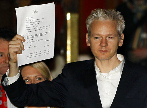 FILE - In this Thursday, Dec. 16, 2010 file photo, WikiLeaks founder Julian Assange holds up a court document for the media after he was released on bail, outside the High Court in London. Judge Vanessa Baraitser has ruled that Julian Assange cannot be extradited to the US. because of concerns about his mental health, it was reported on Monday, Jan. 4, 2021. Assange had been charged under the US
