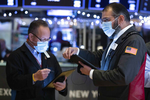 In this photo provided by the New York Stock Exchange, Aman Patel, right, works with a fellow trader on the floor, Tuesday, Jan. 5, 2021. U.S. stocks are wobbling between small gains and losses on Tuesday, a day after dropping to their worst loss in months amid the worsening pandemic and potentially market-moving Senate elections. (Colin Ziemer/New York Stock Exchange via AP) PHOTO CREDIT: Colin Ziemer