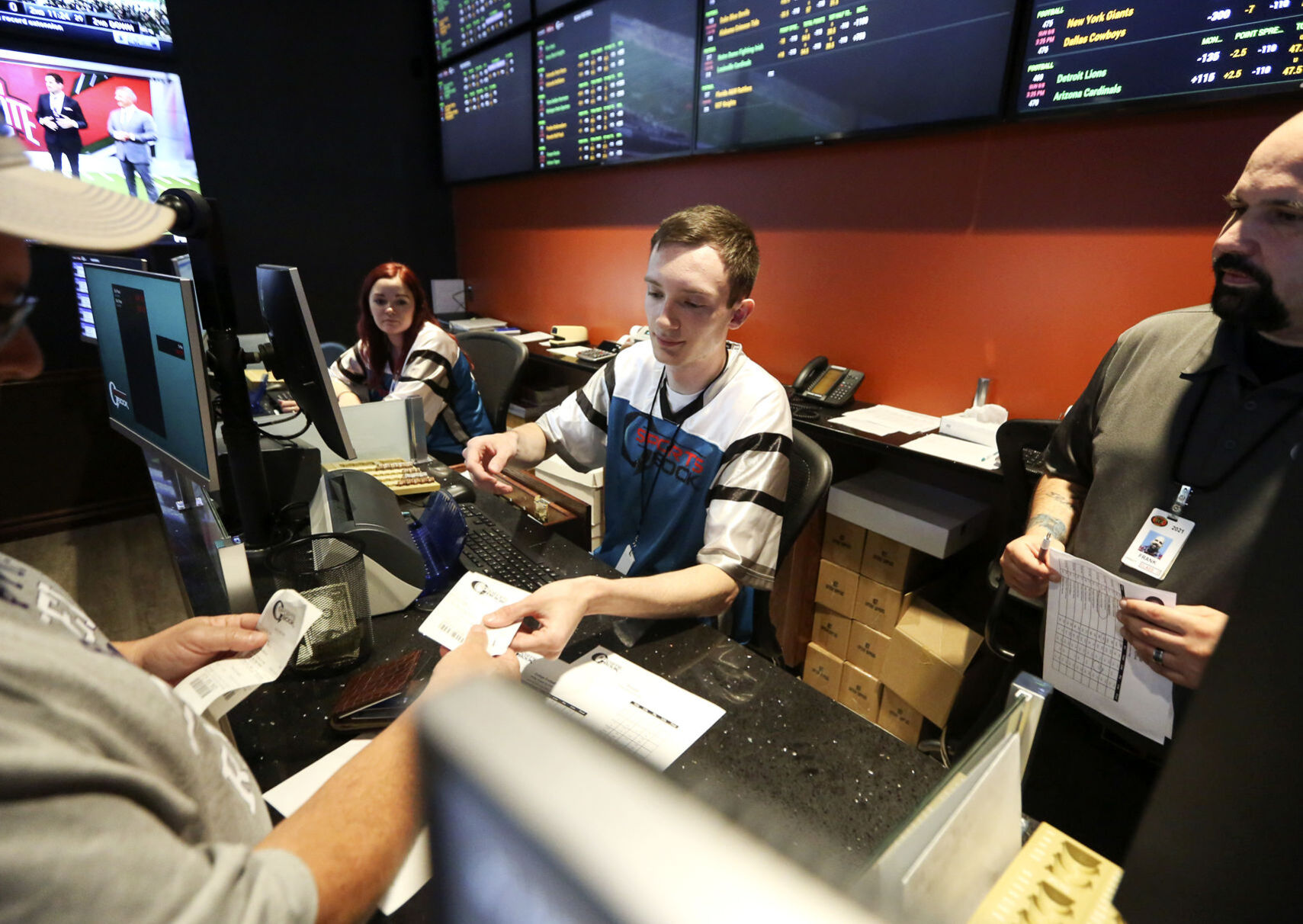Alex Long (center) and Frank Santiago (right) help a customer place a bet at Q Sportsbook inside Q Casino and Hotel in Dubuque in August 2019. PHOTO CREDIT: NICKI KOHL