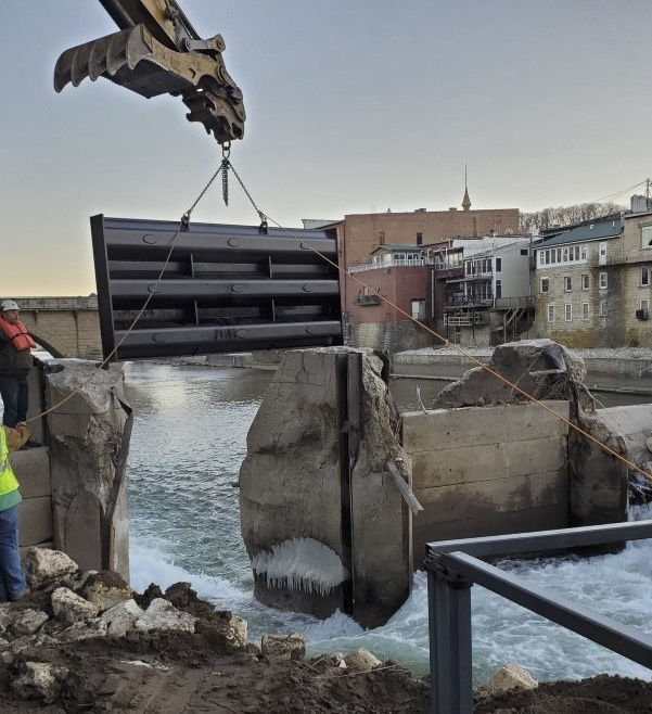 An excavator moves the gate of the Elkader, Iowa dam during repairs. PHOTO CREDIT: Mobile Track Solutions