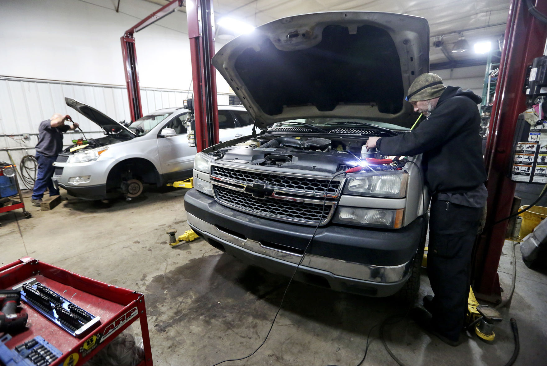 Seth Freeze (left) and Mike Keuter work on vehicles at J’s Performance in Dubuque on Friday. The company plans to move to a new location on Pennsylvania Avenue in the spring. PHOTO CREDIT: NICKI KOHL
