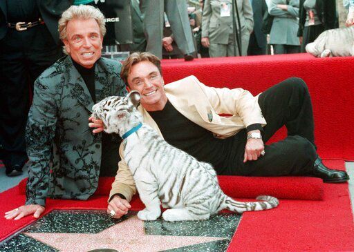 FILE - Illusionists Siegfried Fischbacher, left and Roy Uwe Ludwig Horn pose for photographers with a white tiger cub after they unveiled their star on the Hollywood Walk of Fame in Los Angeles, Calif., on Sept. 23, 1994. German news agency dpa is reporting that Fischbacher, the surviving member of duo Siegfried & Roy has died in Las Vegas at age 81. The news agency said Thursday that Fischbacher’s sister, a nun who lives in Munich, confirmed his death of cancer. Fischbacher’s long-time show business partner, Roy Horn, died in May of complications from COVID-19 at a Las Vegas hospital. (AP Photo/Neil Jacobs, File) PHOTO CREDIT: Neil Jacobs