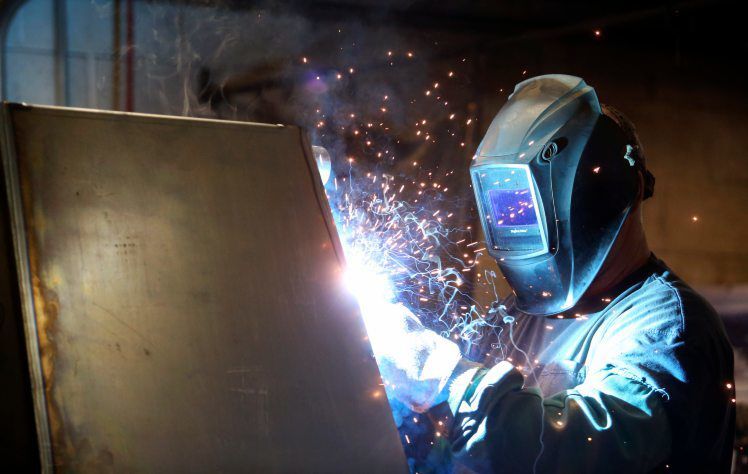 Randy Diesing welds a hydraulic tank at T&J Manufacturing in Maquoketa, Iowa. The company has been producing specialized parts for almost 40 years. It also builds niche products, such as a lowering device that can be used during burials.    PHOTO CREDIT: NICKI KOHL