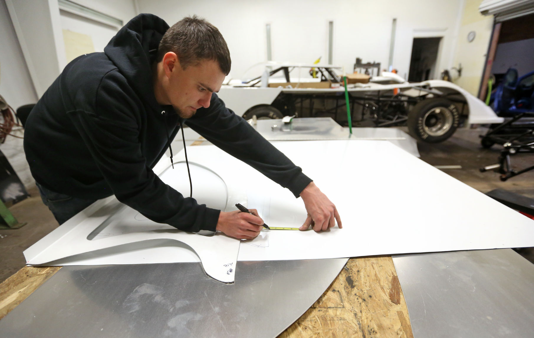 Tyler Madigan measures a piece of sheet metal while working on a roof of a late model racing car at TMR Enterprises in Dubuque on Friday, Jan. 15, 2021. PHOTO CREDIT: JESSICA REILLY