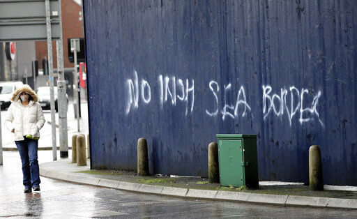 A woman walks past past graffiti with the words 