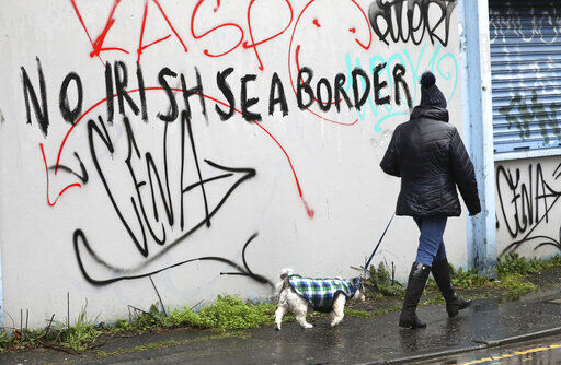 A woman walks her dog past past graffiti with the words 