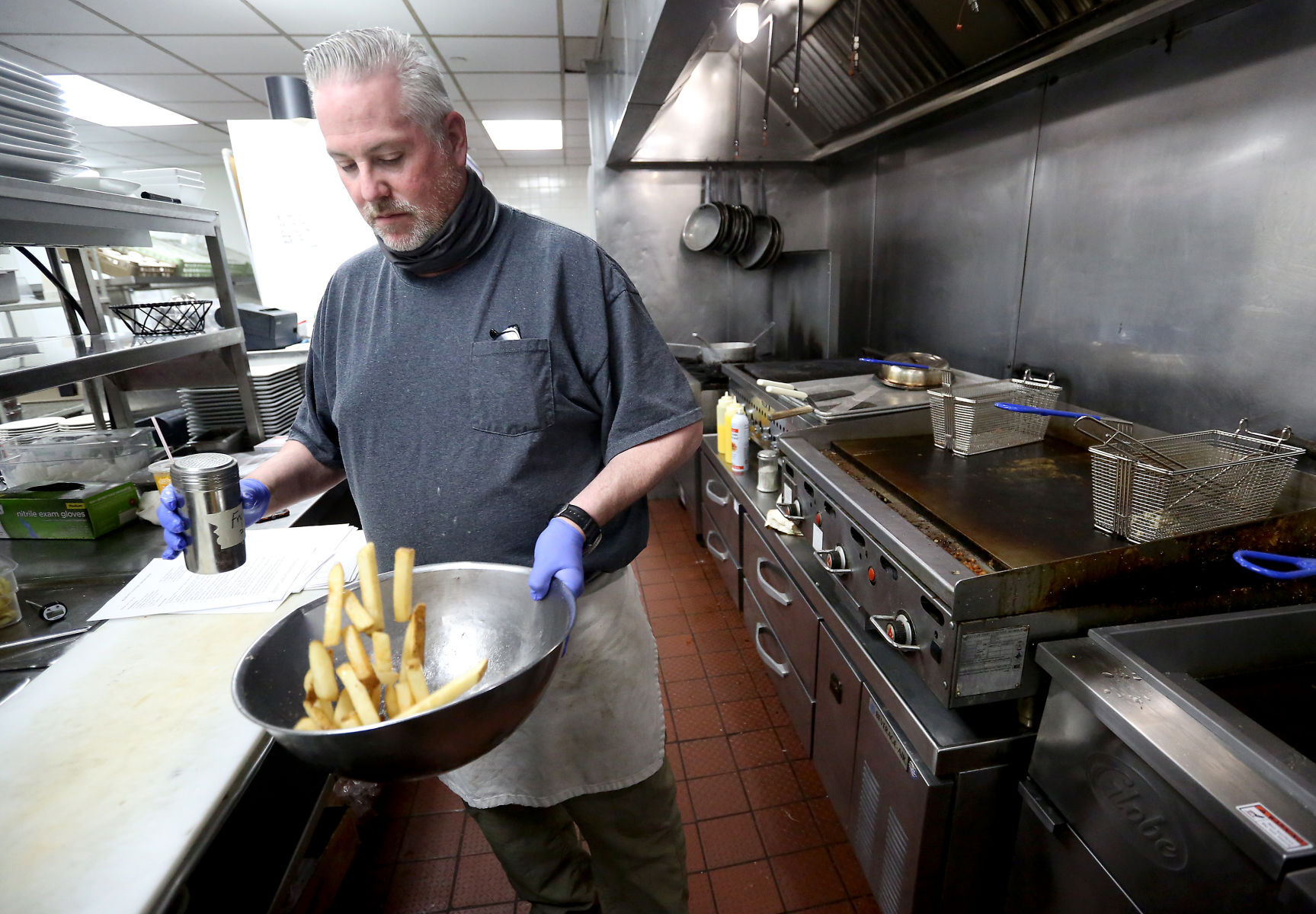 Michael Pratte salts fries while preparing practice meals for Bennigan
