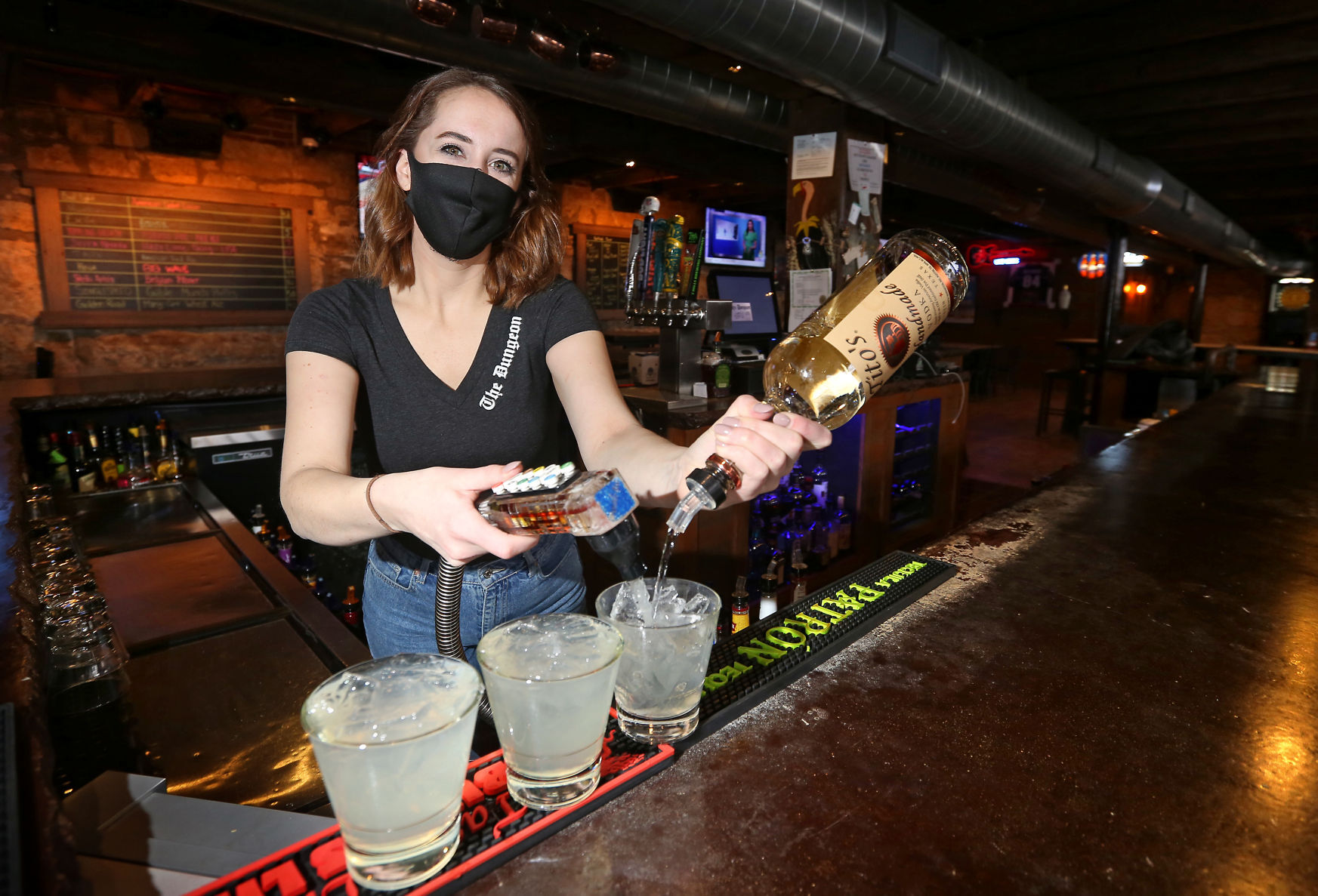 Sarah Knabel, a bartender at The Dungeon in downtown Dubuque, works at the bar on Monday. The business reopened on Thursday. PHOTO CREDIT: JESSICA REILLY