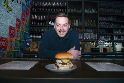 Josh Phillips, the co-owner of Espita, a stylish Mexican restaurant, displays a Ghostburger at his restaurant in downtown Washington. Phillips opened a delivery-only brand called Ghostburger in August to keep Espita’s kitchen running through the winter. He chose burgers because he wanted to reach new customers at a lower price point than Espita. It’s been so successful that Phillips is now scouting for locations for standalone Ghostburger restaurants.  PHOTO CREDIT: Jose Luis Magana