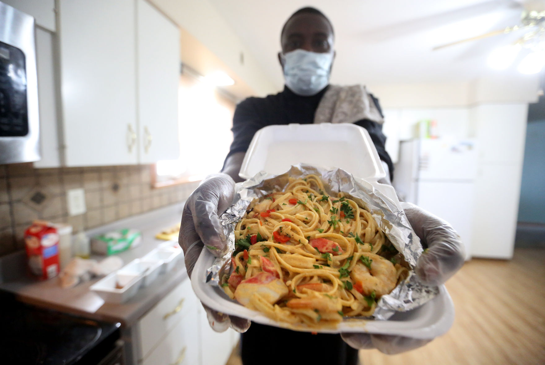 Ty Beard, with Just Like Home Catering, holds up a cajun seafood pasta dish at his home in Asbury, Iowa, on Monday. PHOTO CREDIT: JESSICA REILLY