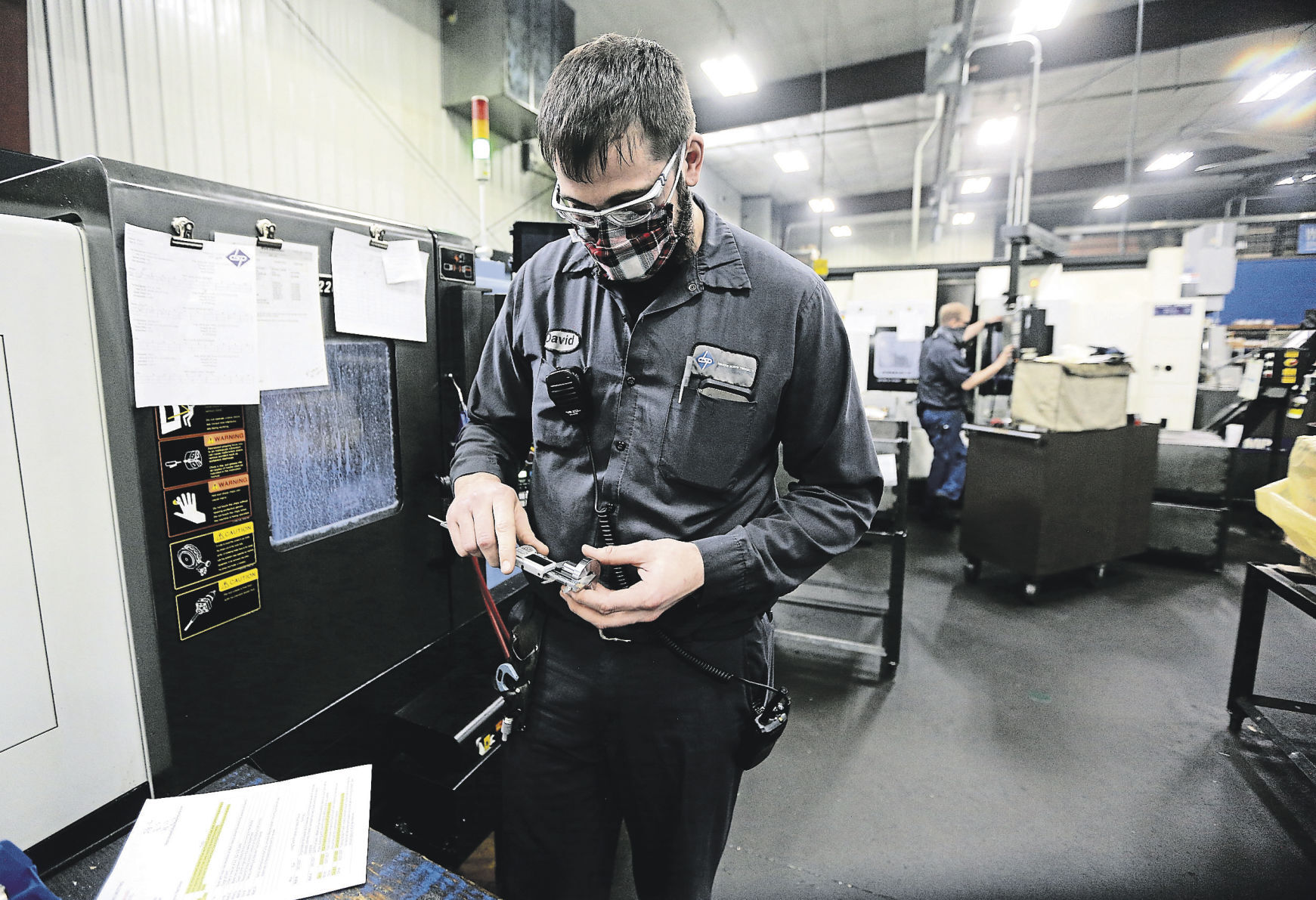 David Bentz, applications engineer technician at Dubuque Screw Products, Inc., checks over a part produced in the Dubuque plant recently.    PHOTO CREDIT: Dave Kettering