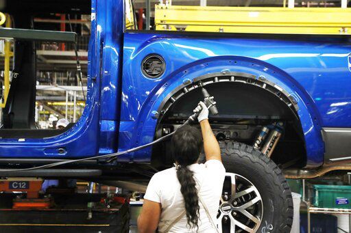 FILE- In this Sept. 27, 2018, file photo a United Auto Workers assemblyman works on a 2018 Ford F-150 truck being assembled at the Ford Rouge assembly plant in Dearborn, Mich. Ford Motor Co. said Thursday, Feb. 4, 2021, that it will cut shifts at two of its U.S. manufacturing plants next week, due to the worldwide chip shortage that has also impacted other automakers. Ford will cut shifts at its Dearborn, Mich., facility and Kansas City, Mo., plant; both produce the F-150 pickup truck, Ford