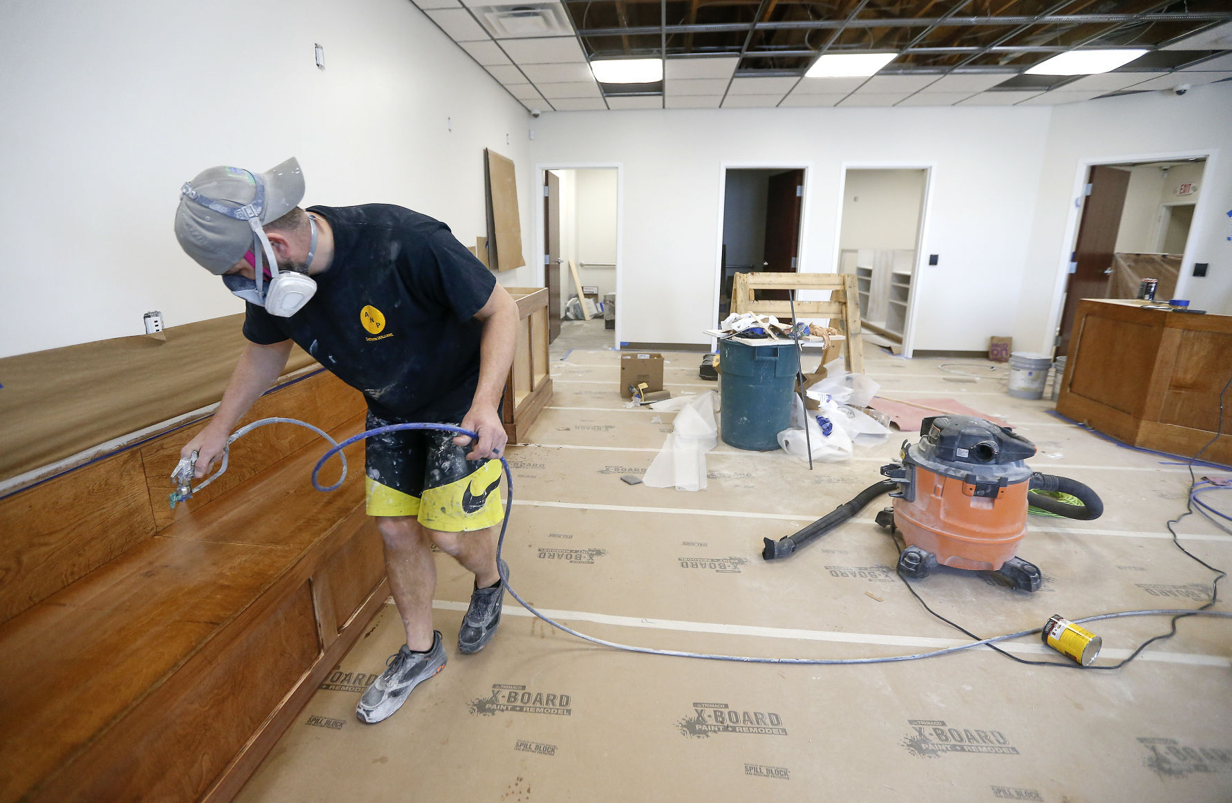 Greg Lehman, of Lehman Painting, sprays lacquer onto wooden seating in the lobby of the future home of an adult-use cannabis dispensary on Illinois 35 in East Dubuque, Ill. PHOTO CREDIT: Dave Kettering