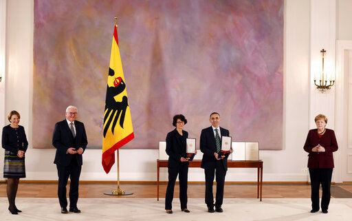Ozlem Tureci, tgird left, and her husband Ugur Sahin, 2nd right, both scientists and founders of BioNTech, pose with their orders after they were awarded the Federal Cross of Merit (Bundesverdienstkreuz) by German President Frank-Walter Steinmeier, 2nd left, on March 19, 2021 at the presidential Bellevue Palace in Berlin, Germany, Friday, March 19, 2021. At right is German Chancellor Angela Merkel, at left is the wife of the German President Elke Buedenbender. (Odd Andersen/Pool Photo via AP) PHOTO CREDIT: Odd Andersen