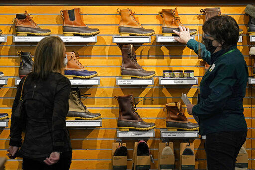 A salesperson helps a customer shopping for Bean Boots at the L.L. Bean flagship retail store, Thursday, March 18, 2021, in Freeport, Maine. Maine-based retailer L.L. Bean saw the best sales in nearly a decade during pandemic. Officials say the Freeport-based retailer started its fiscal year with store closings and worries about survival but the company weathered the turbulent times to revenue growth of 5%. (AP Photo/Robert F. Bukaty) PHOTO CREDIT: Robert F. Bukaty