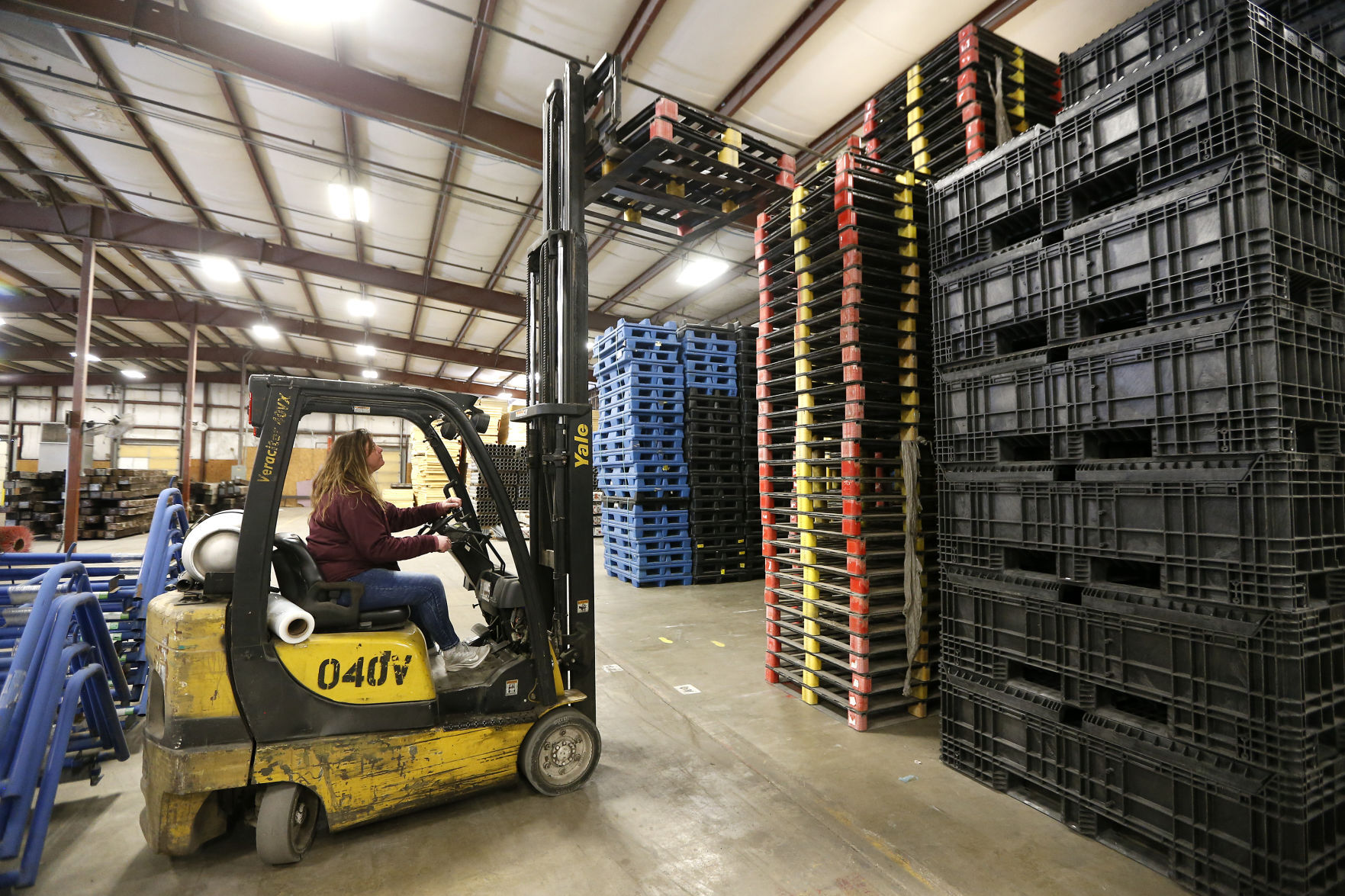 Jessi Walker, manager of Repurposed Materials in Maquoketa, Iowa, stacks up flat pallets that are among the many items for sale.    PHOTO CREDIT: Dave Kettering