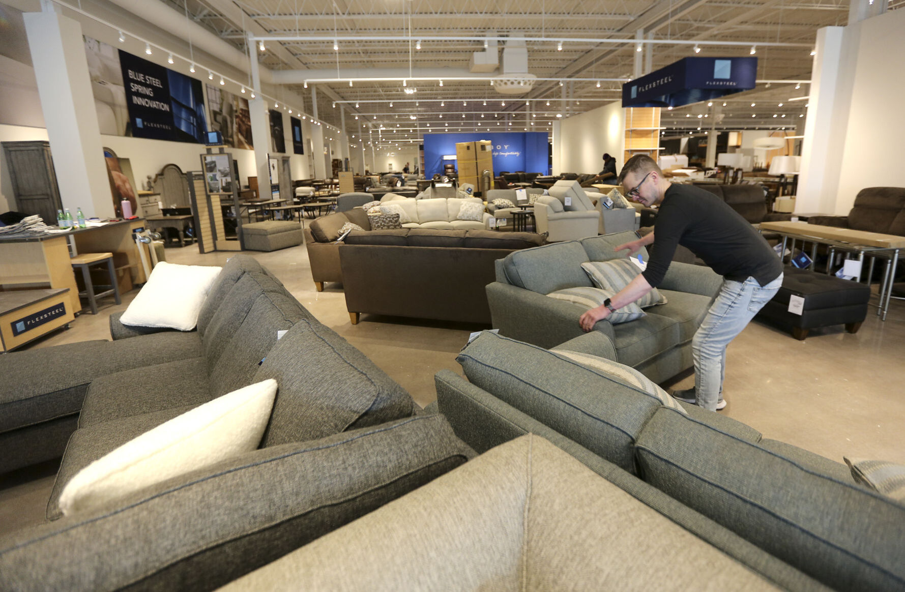 Will Ambroson, lead designer with Flexsteel Industries, arranges furniture Thursday inside the new Slumberland Furniture store, located in Plaza 20 in Dubuque. The store is scheduled to open on Saturday, March 27. PHOTO CREDIT: Dave Kettering