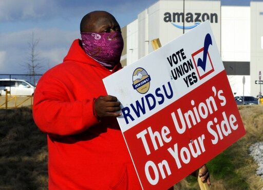 Michael Foster of the Retail, Wholesale and Department Store Union holds a sign outside an Amazon facility where labor is trying to organize workers in Bessemer, Ala.  PHOTO CREDIT: Jay Reeves