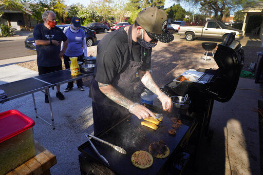 Chef Mike Winneker prepares tacos in front of his home in Scottsdale, Ariz. Beaten down by the pandemic, many laid-off or idle restaurant workers have pivoted to dishing out food with a taste of home. Some have found their entrepreneurial side, slinging their culinary creations from their own kitchens. PHOTO CREDIT: Ross D. Franklin