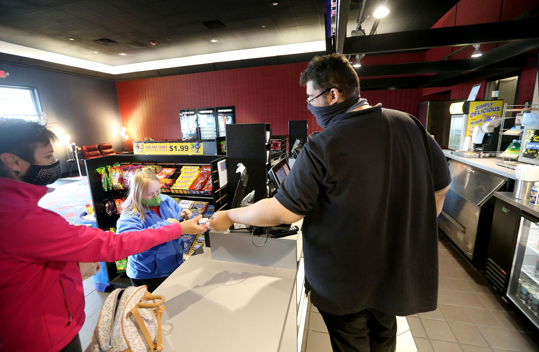 Dominik Cok hands tickets to Molly Ploessl (left) and Emily Cloos, both of Bellevue, Iowa, at Phoenix Theatres in Dubuque on Thursday. PHOTO CREDIT: JESSICA REILLY