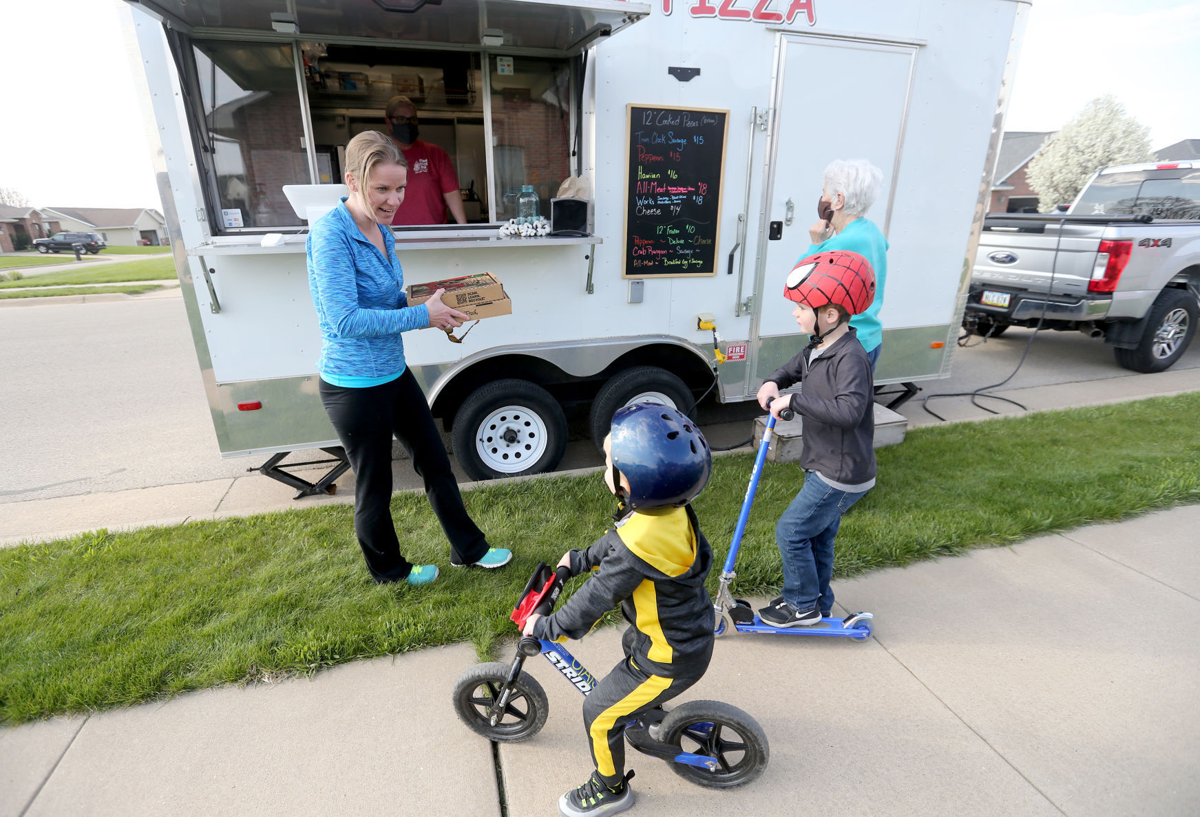Jennifer Billmeyer grabs a pizza from Irene Nelson, co-owner of Town Clock Inn, with her sons Oliver (left), 3, and Owen, 6, on Thursday in Asbury, Iowa. PHOTO CREDIT: JESSICA REILLY