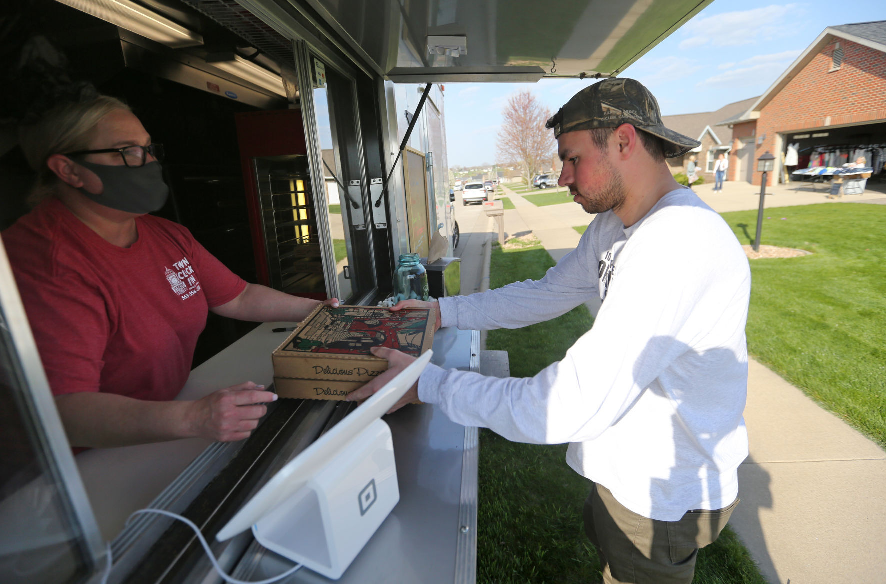 Caleb Snyder grabs a pizza from Irene Nelson, co-owner of Town Clock Inn, on Thursday in Asbury, Iowa. PHOTO CREDIT: JESSICA REILLY