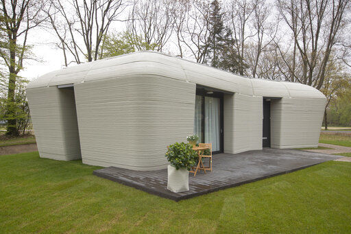 Exterior view of the 3D-printed 94-square meters (1,011-square feet) two-bedroom bungalow resembling a boulder with windows in Eindhoven, Netherlands, Friday, April 30, 2021. The fluid, curving lines of its gray walls look natural. But they are actually at the cutting edge of housing construction in the Netherlands and around the world. They were 3D printed at a nearby factory. (AP Photo/Peter Dejong) PHOTO CREDIT: Peter Dejong