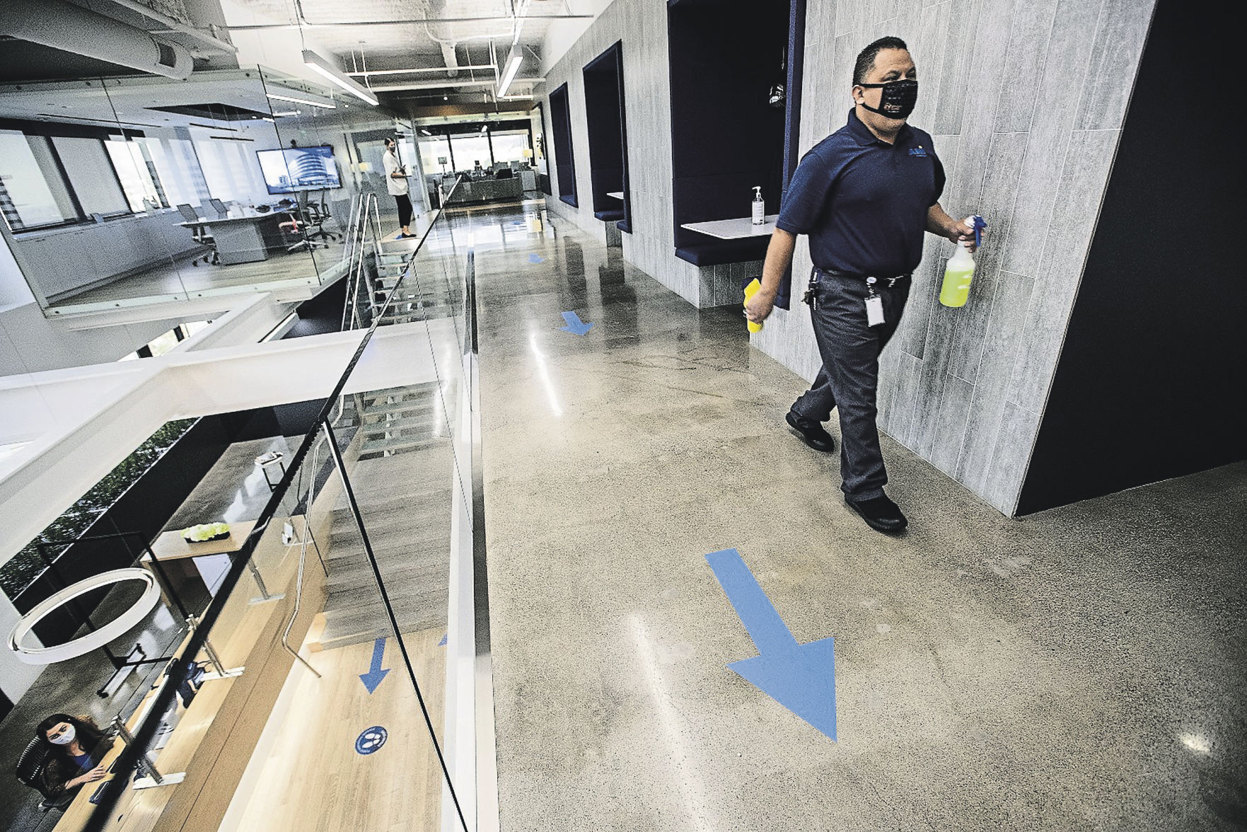 Saul Mendoza, with building maintenance, walks with disinfectant while cleaning a common area at Hudson Pacific Properties, a big office landlord on Wilshire Boulevard in Los Angeles. Arrows taped on the floor are to maintain one-way foot traffic to guard against the spread of the coronavirus.    PHOTO CREDIT: Mel Melcon