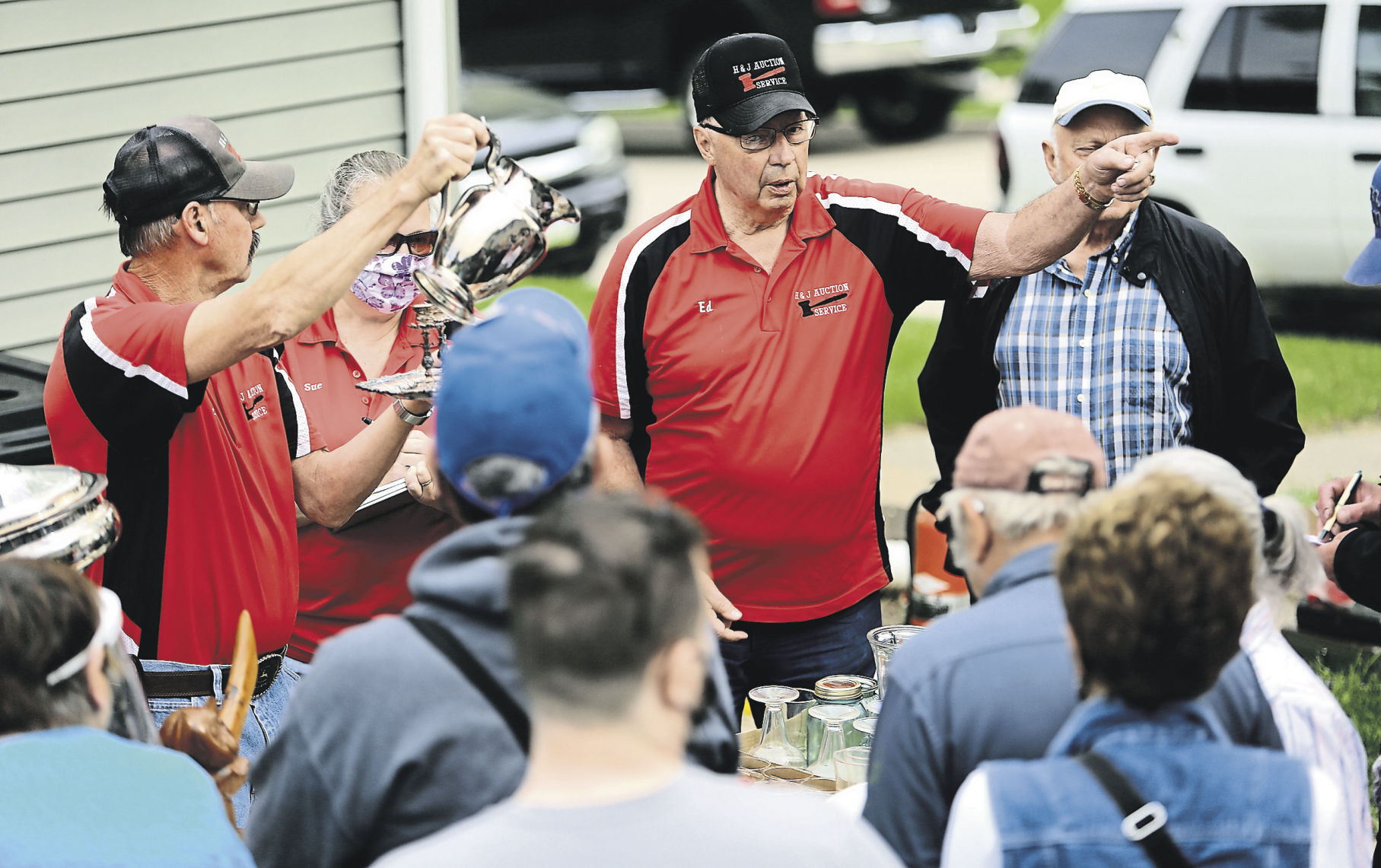 Ed Hess (center), co-owner of H&J Auction Service, points to a customer who made a bid during an estate auction held in Dubuque. The business began in 1992. The owners say that they have sold a little bit of everything through the years. PHOTO CREDIT: Dave Kettering