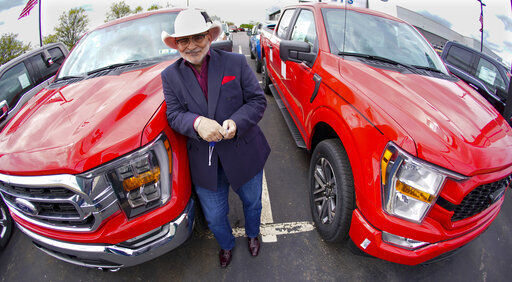 In this photo made on Thursday, May 6, 2021, Shults Ford dealership owner Richard Bazzy stands between two of the remaining Ford F150 pickups on the front line on their dealership lot in Wexford, Pa. Ford is warning that it expects to make only half the normal number of vehicles from now through June. Bazzy normally stocks 400-500 pickup trucks at his three Ford dealers, but is down around 100. He