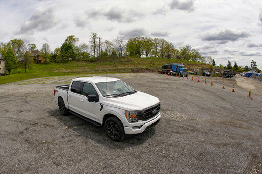 In this photo made on Thursday, May 6, 2021, a salesman from the Shults Ford dealership in Wexford, Pa. sits in one of the Ford F150 trucks at their nearby empty pickup truck inventory storage lot. Ford is warning that it expects to make only half the normal number of vehicles from now through June. Bazzy normally stocks 400-500 pickup trucks at his three Ford dealers, but is down around 100. He
