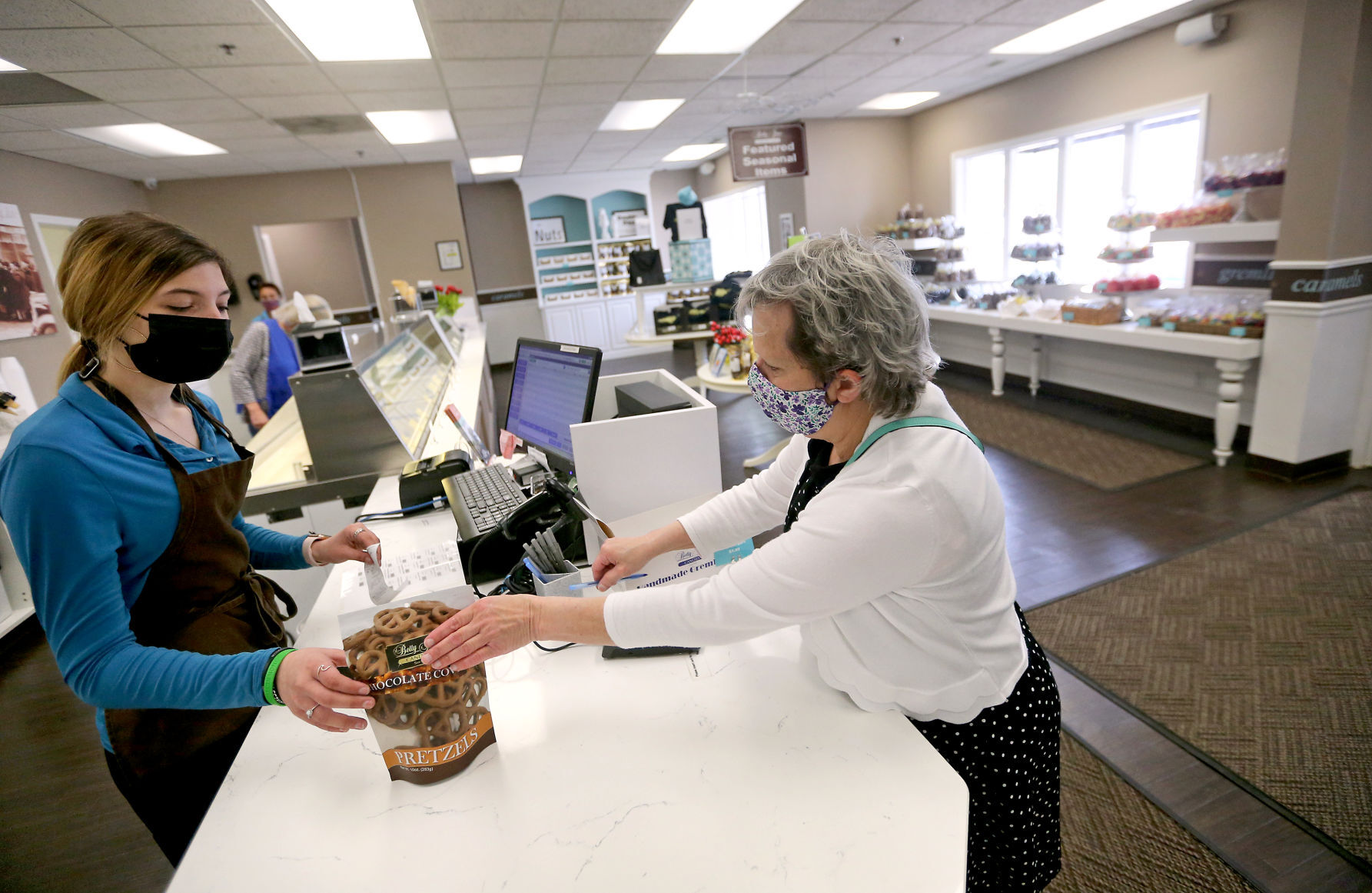 Jaylynn Hirsch (left) rings up a purchase for Tracey Grentz, of Dubuque, at Betty Jane Candies