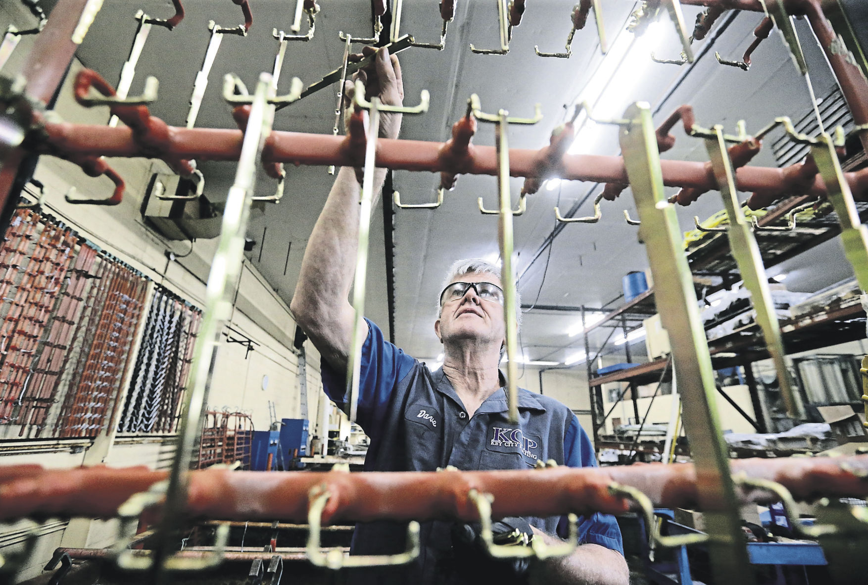 Dave Finn takes finished chain gauges from a rack at Key City Plating in Dubuque. PHOTO CREDIT: JESSICA REILLY