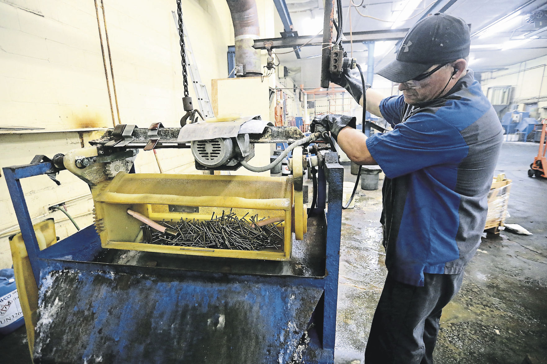 Troy Mulholland removes items from a barrel at Key City Plating in Dubuque. PHOTO CREDIT: JESSICA REILLY