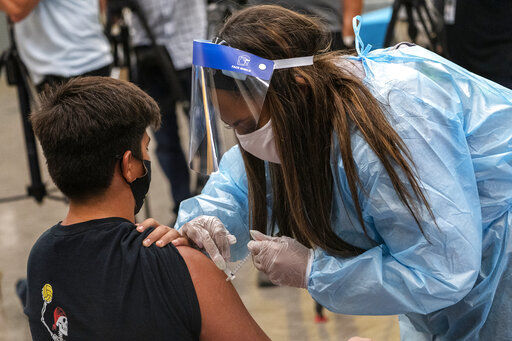 High school water polo team member Marc Bugarin, 15, is vaccinated at a school-based COVID-19 vaccination clinic for students 12 and older in San Pedro, Calif., Monday, May 24, 2021. School districts from California to Michigan are offering free prom tickets and deploying mobile vaccination teams to schools to inoculate students 12 and up so everyone can return to classrooms in the fall. They are also enlisting students who have gotten shots to press their friends to do the same. (AP Photo/Damian Dovarganes) PHOTO CREDIT: Damian Dovarganes