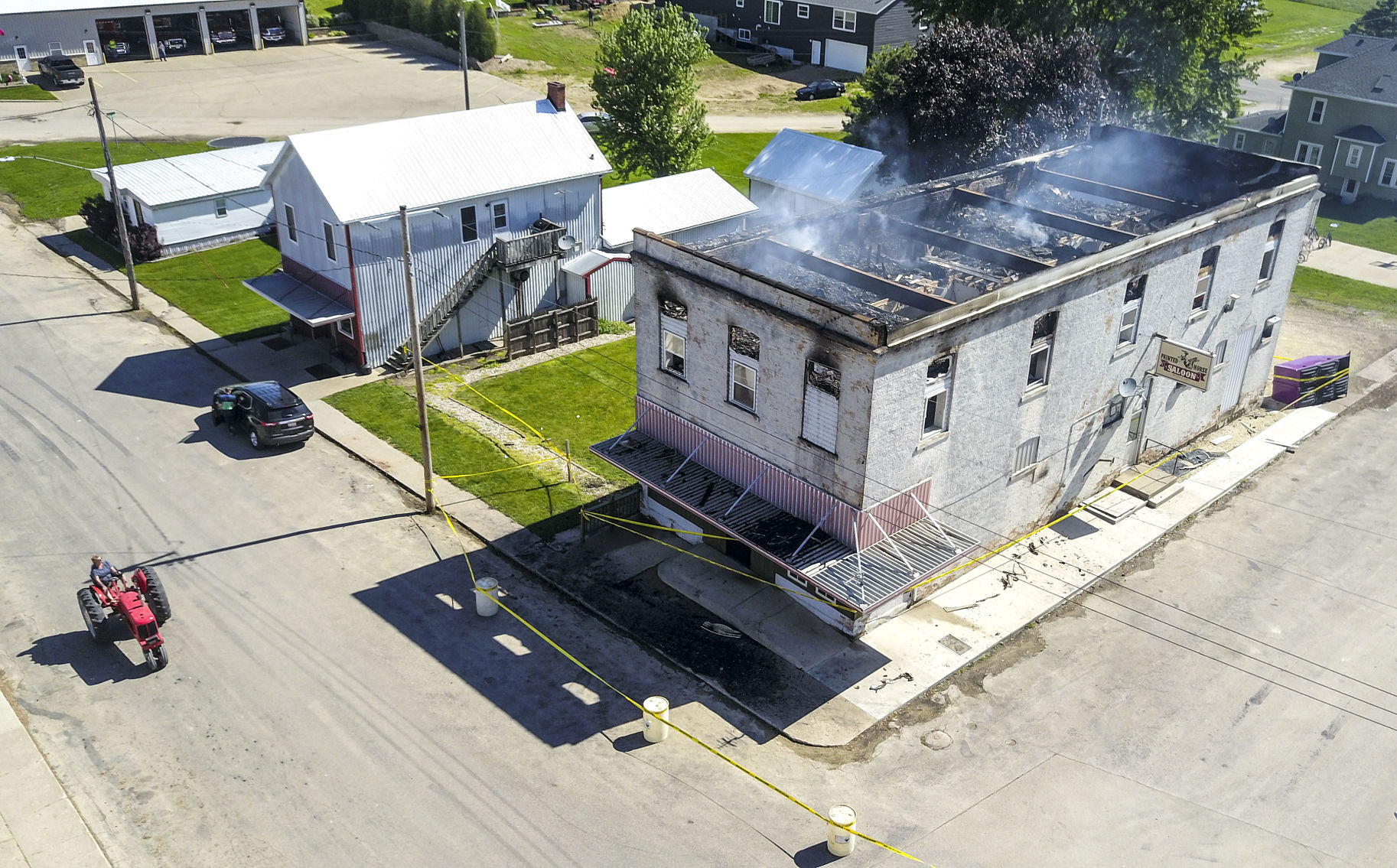 A passerby looks at a fire still smoldering after a fire damaged the building that housed the Painted Horse Saloon and second-floor apartments at 268 Jess St. in Bernard, Iowa, in the early morning hours of Wednesday. PHOTO CREDIT: DAVE KETTERING