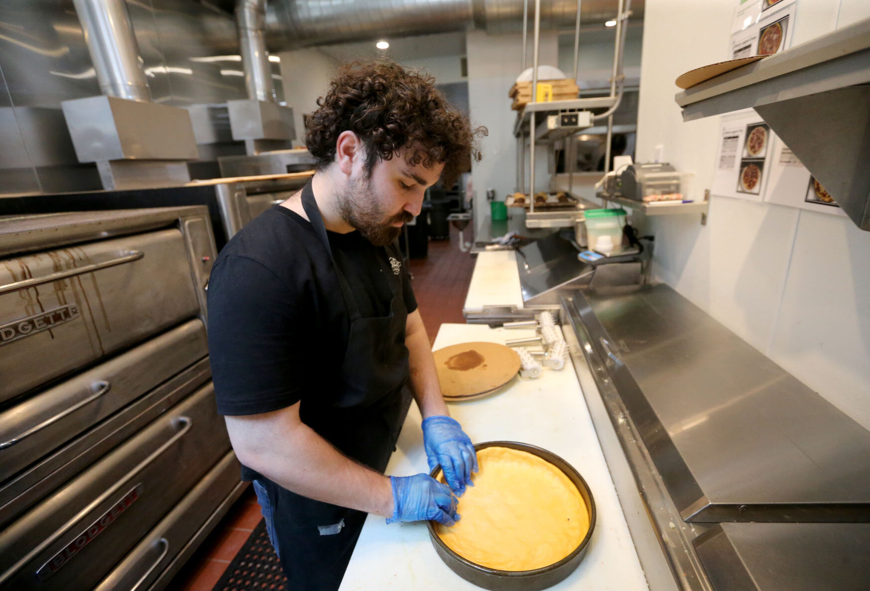 Nicholas Lindsay stretches dough in a pan at Gino