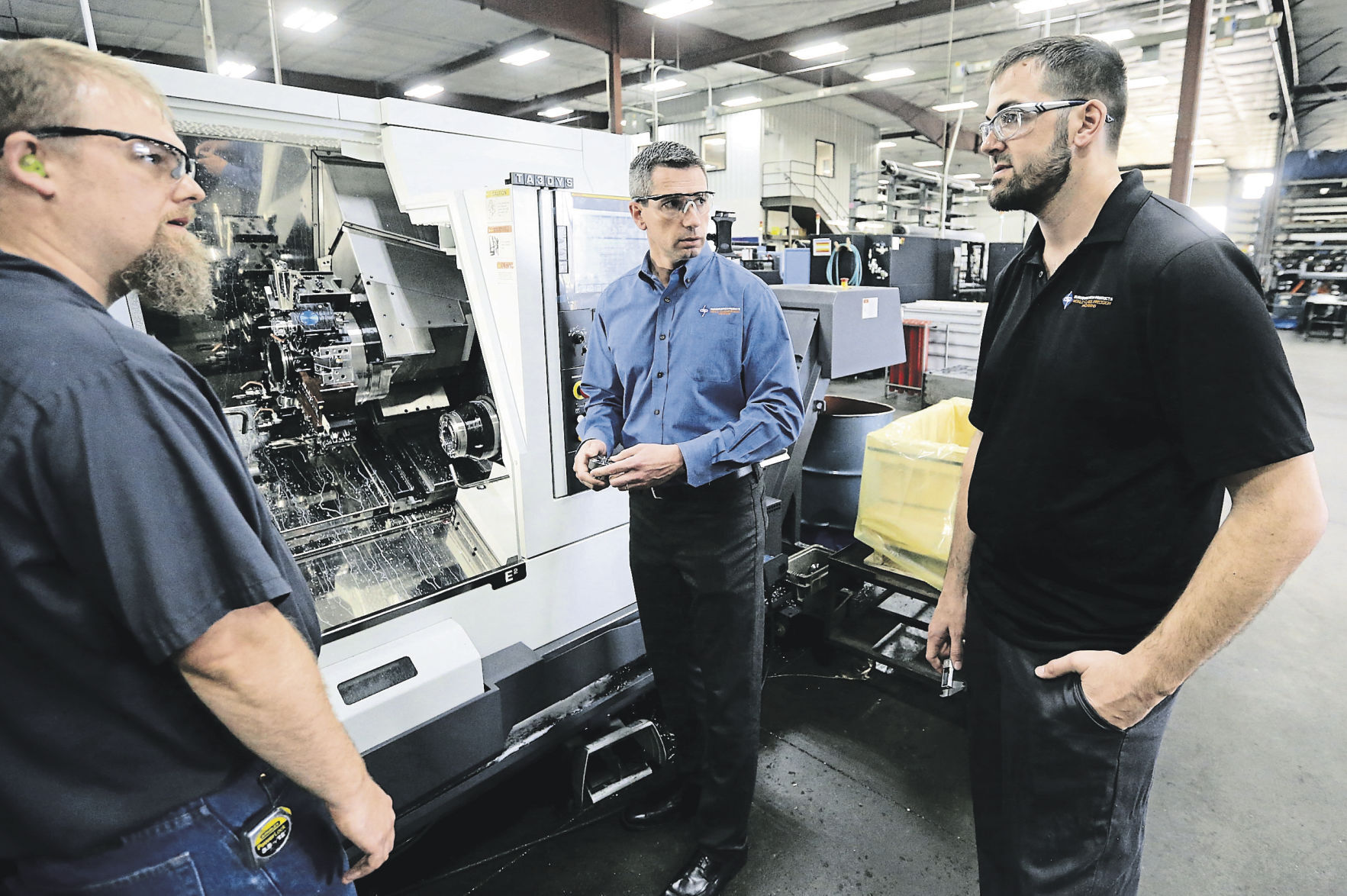 Matt Anderson (from left), Matt Scherr, president of Dubuque Screw Products, and David Bentz talk at the facility in Dubuque. PHOTO CREDIT: JESSICA REILLY