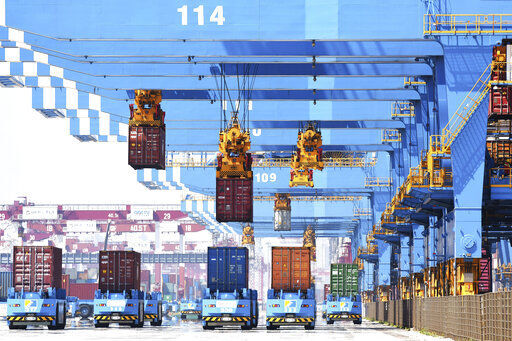 Gantry cranes move containers onto transporters at a port in Qingdao in eastern China