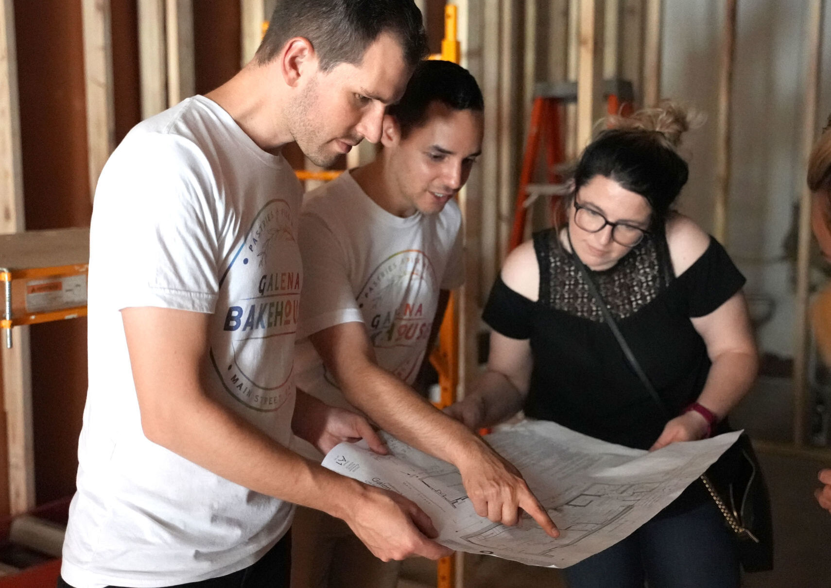 (From left) Geoff Karnish and Alex Arroyo, co-owners of the Galena Bakehouse, stand next to Marisa Arroyo, of Cleveland, Ohio, while showing off building plans during a tour of the interior of the building at 421 S. Main St. in Galena, Ill. They plan to be open for business in early August. Photo taken on Saturday, June 19, 2021.    PHOTO CREDIT: PAUL KURUTSIDES