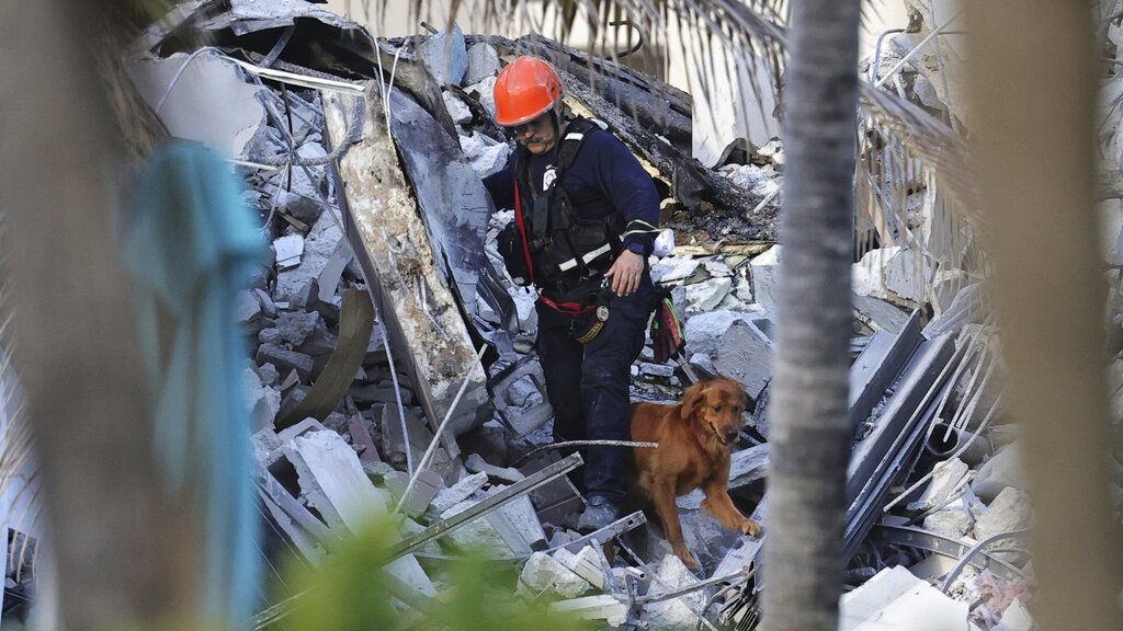 Fire rescue personnel conduct a search and rescue with dogs through the rubble of the Champlain Towers South Condo after the multistory building partially collapsed in Surfside, Fla. PHOTO CREDIT: David Santiago