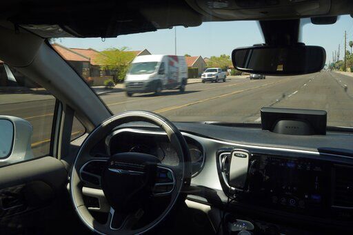 A Waymo minivan moves along a city street with an empty driver’s seat as a moving steering wheel drives passengers during an autonomous vehicle ride in Chandler, Ariz., on April 7. PHOTO CREDIT: Ross D. Franklin