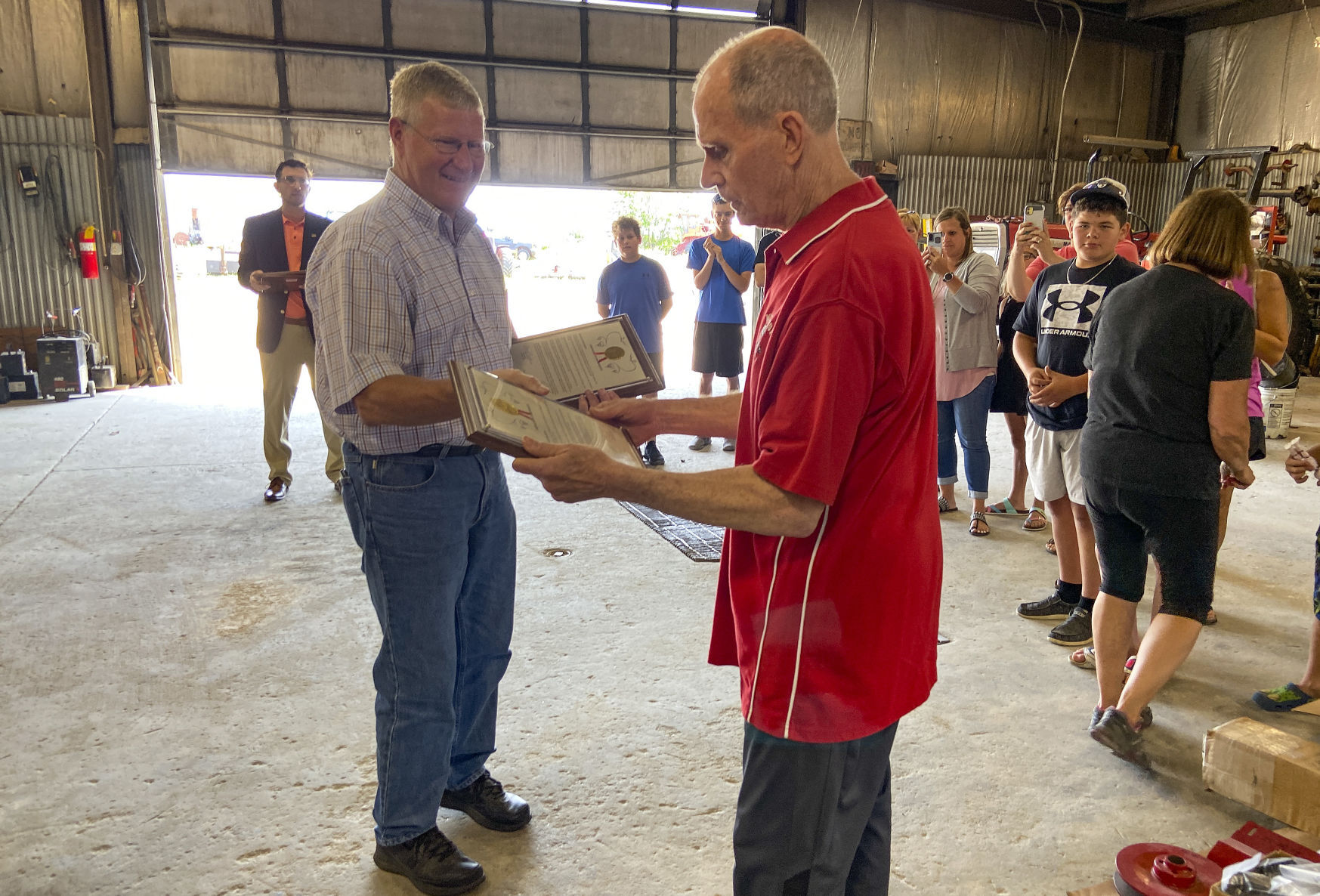 Wisconsin Sen. Howard Marklein, R-Spring Green, hands a legislative citation to Larry Freiburger, a retired co-founder of Grant Equipment Co. in Cuba City, Wis., on Friday. PHOTO CREDIT: Bennet Goldstein