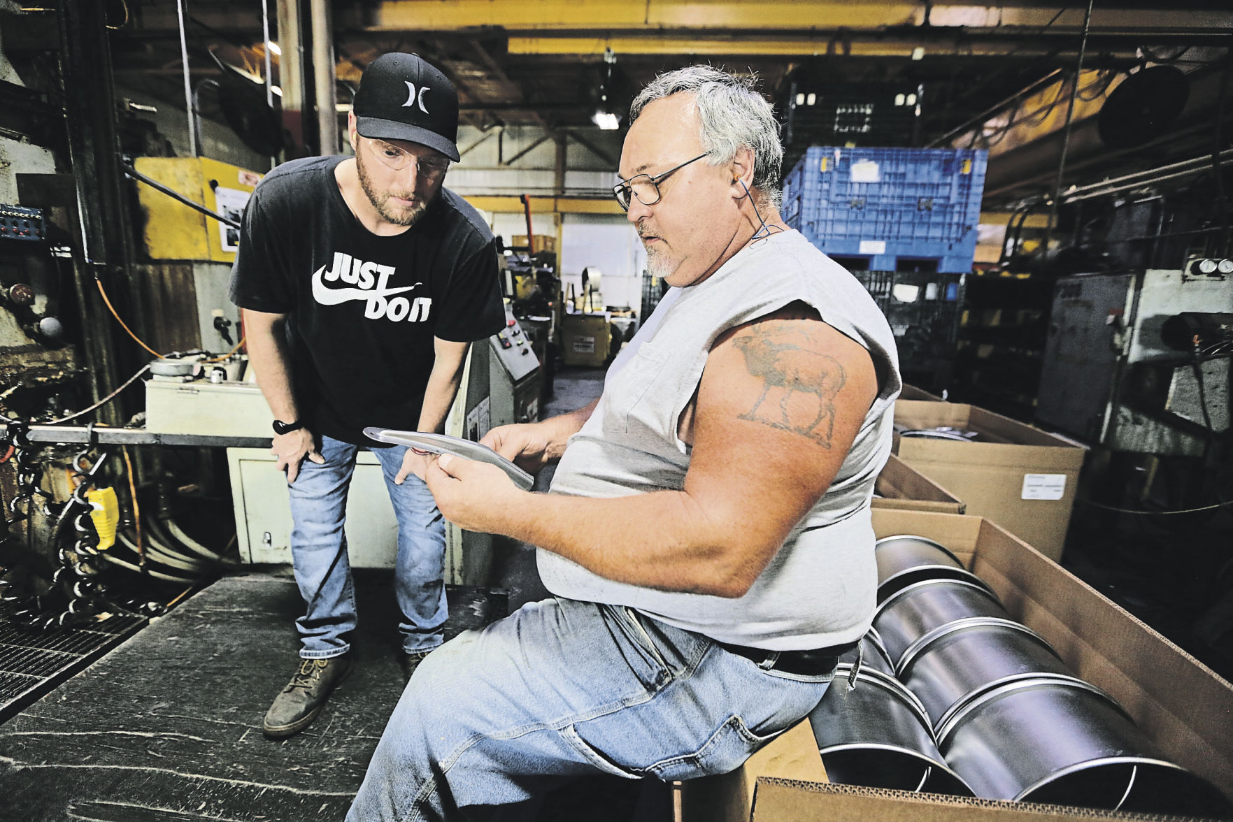 Press operator Zachary Carr (left) looks over a part with long-time employee Walter Rupert at Uelner Precision Tools & Dies.    PHOTO CREDIT: Dave Kettering