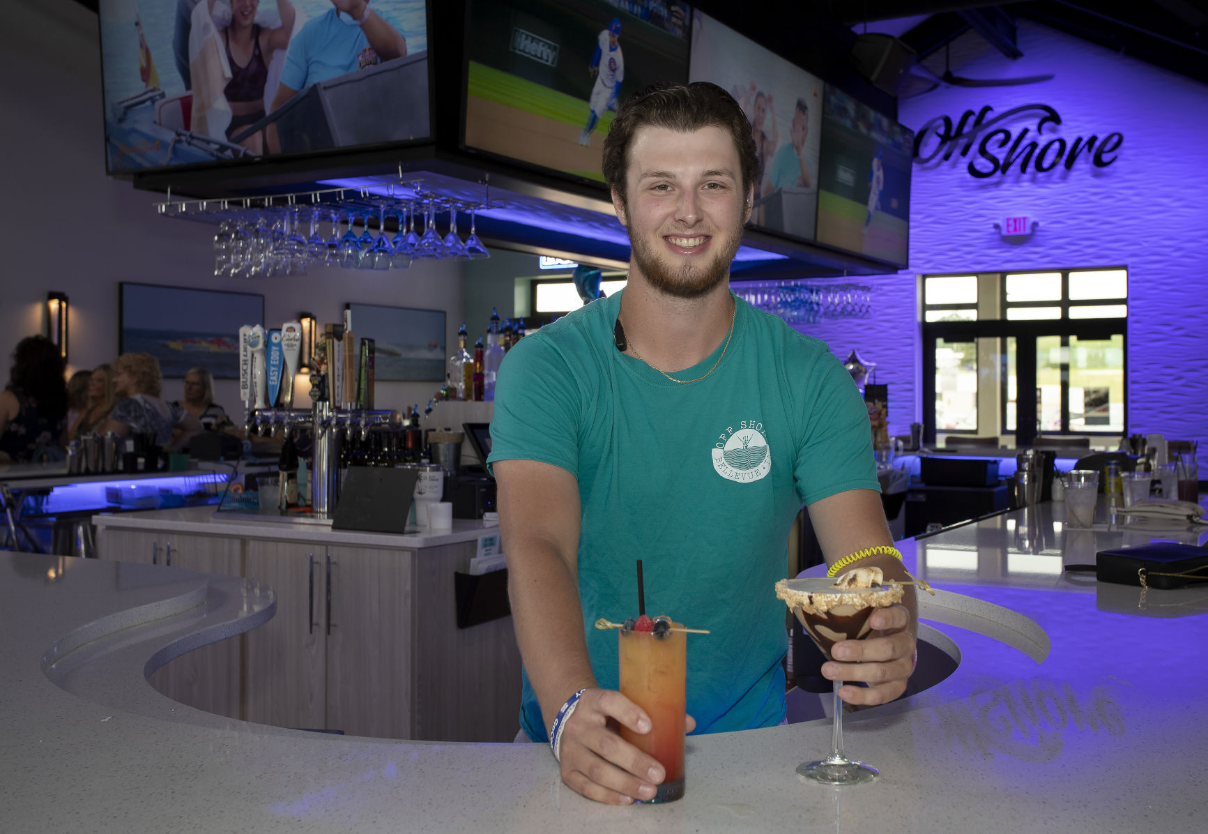 Bartender Aidan Germaine holds two of Off Shore Bar & Grill’s signature drinks — the Cigarette (left) and the Peanut Butter S’mores Martini — in Bellevue, Iowa, on Thursday. PHOTO CREDIT: Stephen Gassman